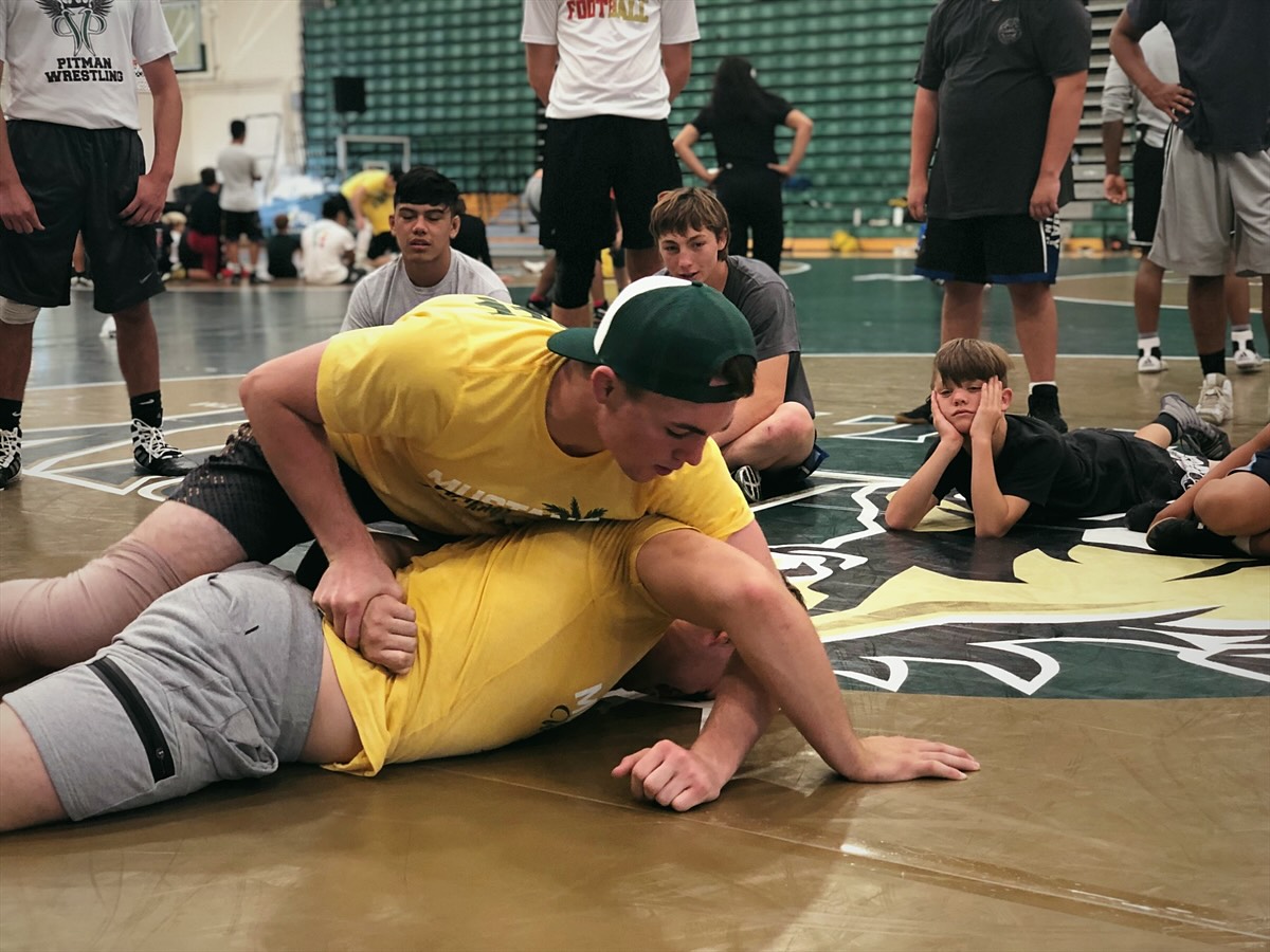 Two camp staff members demonstrate a position on the mat while campers watch
